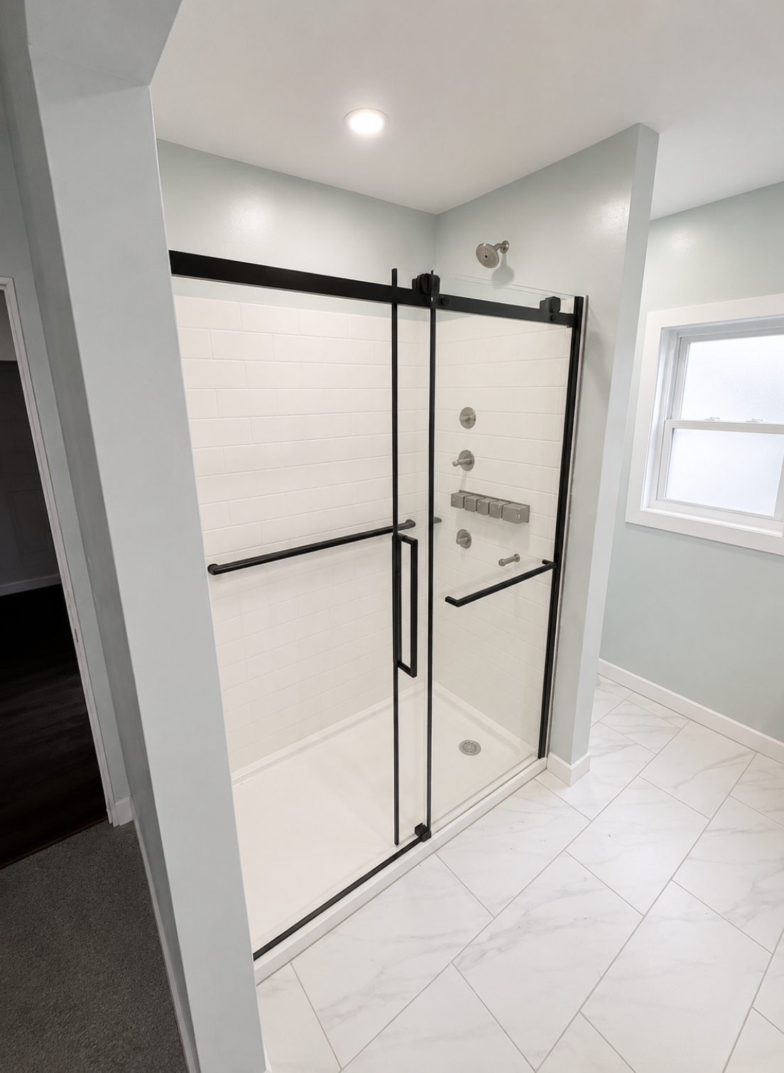 Bathroom with black fixtures and marble-look tile shower
